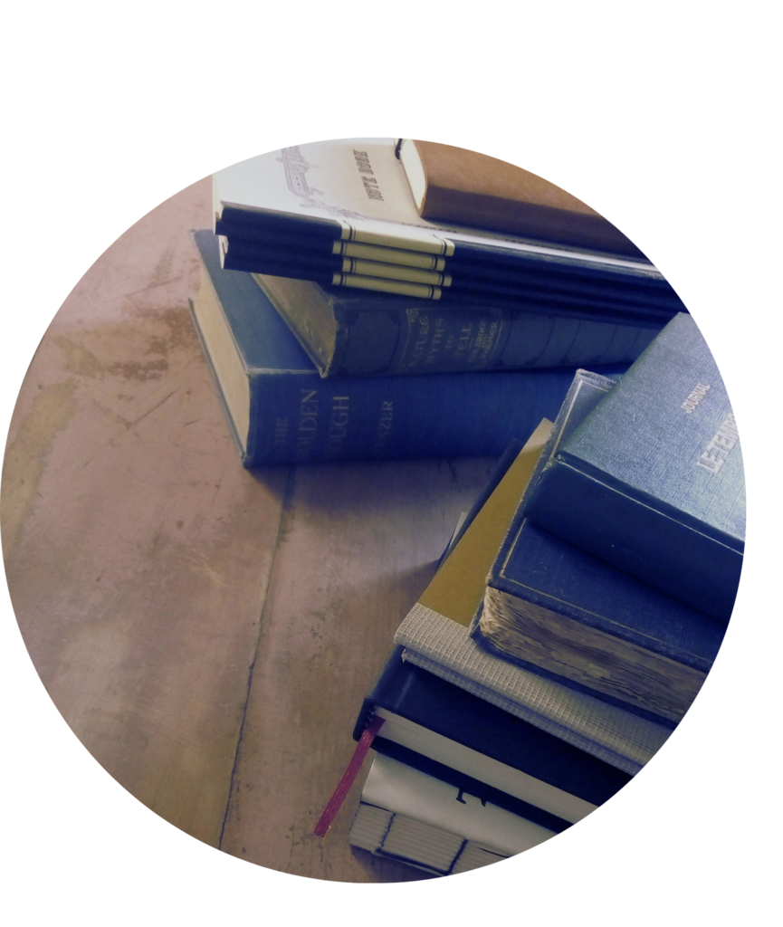 A circular photograph showing two stacks of notepads and books belonging to L.B. Hazelthorn. In the great tradition of writers everywhere most of these notebooks have never been used but they do look nice in pictures. 